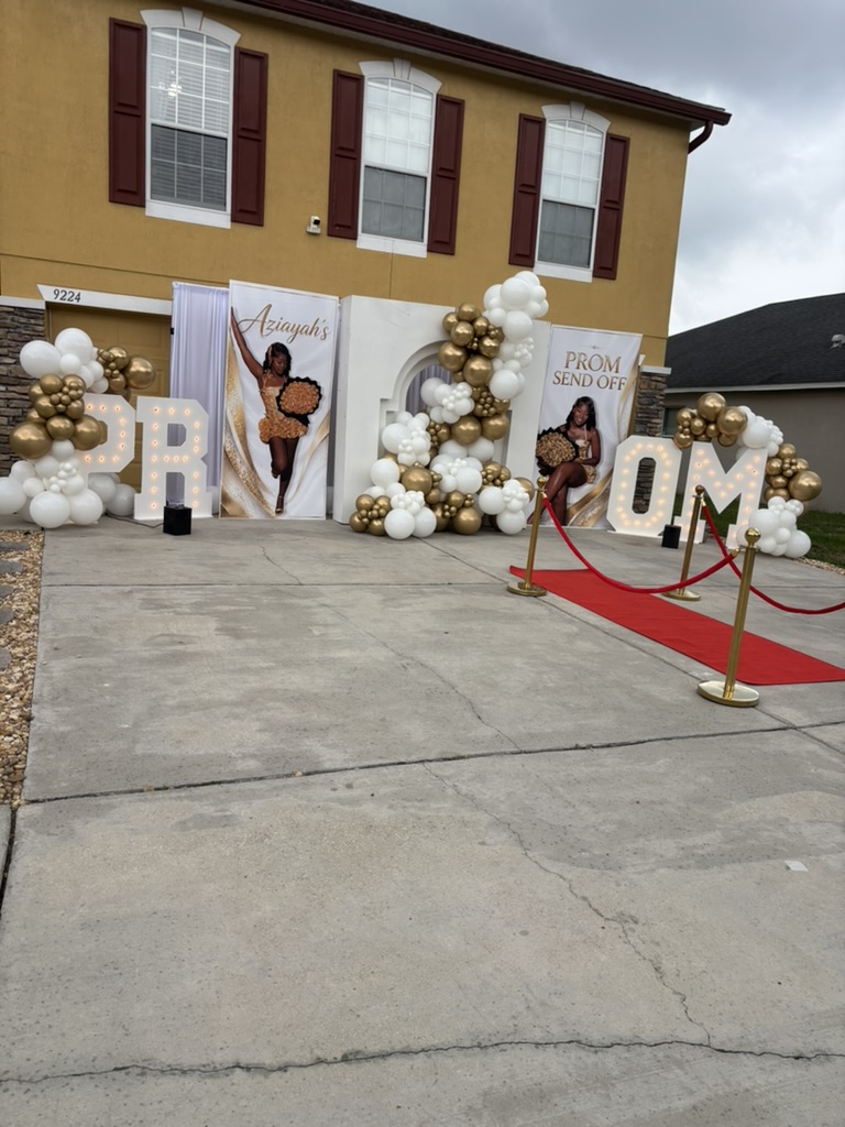 Prom send-off entrance with a balloon garland, marquee letters and a red carpet