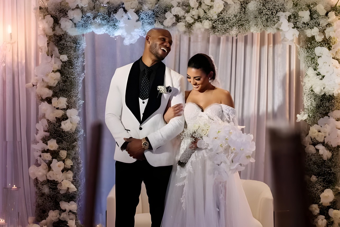 Bride and groom beneath a white floral wedding arch styled by Sharp Designs